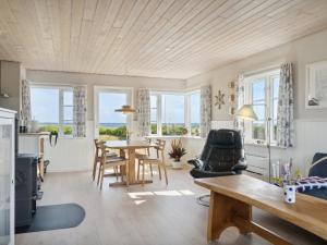 Holiday Home Mirkka - 50m from the sea in Funen by Interhome في Asperup: غرفة معيشة مع طاولة وكراسي ونوافذ