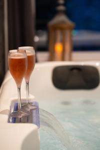 - deux verres à champagne assis sur une table à côté d'une piscine dans l'établissement Jacuzzi- Chambre Secrète- Love Room- Une Pause à Deux, à Château-Landon