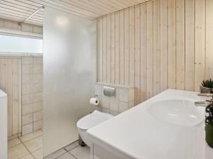 y baño con aseo blanco y lavamanos. en Holiday Home Sari - 250m from the sea in SE Jutland by Interhome, en Sønderby