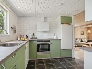 cocina con armarios verdes y nevera blanca en Holiday Home Sari - 250m from the sea in SE Jutland by Interhome, en Sønderby