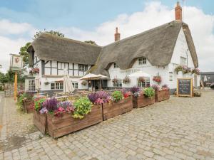 a thatched cottage with flowers in front of it at The Old Bakehouse in Marlborough