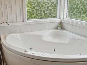 La salle de bains est pourvue d'une baignoire blanche et de 2 fenêtres. dans l'établissement Holiday Home Asko - 350m from the sea in Djursland and Mols by Interhome, à Ebeltoft
