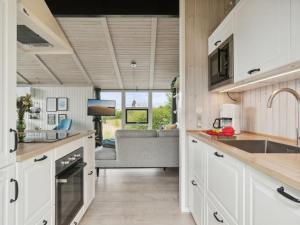 une cuisine avec des placards blancs et un salon dans l'établissement Holiday Home Asko - 350m from the sea in Djursland and Mols by Interhome, à Ebeltoft