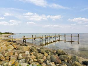 una playa con rocas y un muelle en el agua en Holiday Home Sander - 10m to the inlet in The Liim Fiord by Interhome, en Roslev