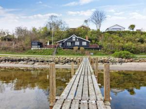 un puente de madera sobre un cuerpo de agua con una casa en Holiday Home Sander - 10m to the inlet in The Liim Fiord by Interhome, en Roslev