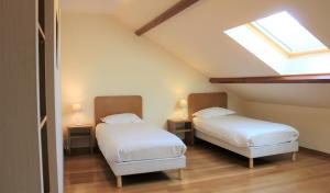 een zolderkamer met 2 bedden en een dakraam bij La Bullote - Gîtes - Paris Roissy in Villeneuve-sous-Dammartin