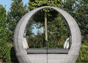 a wicker chair with a window in a garden at Lincoln Holiday Retreat Little House in Lincoln