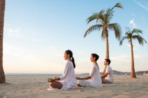 three people sitting in meditation on the beach at Hyatt Ziva Los Cabos - All Inclusive in San José del Cabo