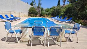 a group of chairs and a table and a pool at Stunning Villa with Pool, Table tennis, Table soccer and a Pool table in Naxxar