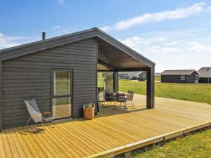 eine Hütte mit einer Terrasse mit einem Tisch und Stühlen in der Unterkunft Holiday Home Serey - 1-4km from the sea in NW Jutland by Interhome in Løkken