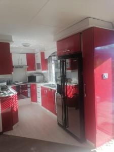cocina con armarios rojos y nevera negra en Rose-Lee Cottage, en Durban