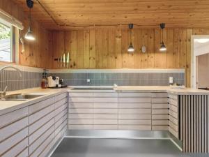 a kitchen with white cabinets and wooden walls at Holiday Home Anya - 600m from the sea in NE Jutland by Interhome in Hals