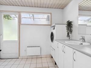 a white kitchen with a sink and a washing machine at Holiday Home Anya - 600m from the sea in NE Jutland by Interhome in Hals