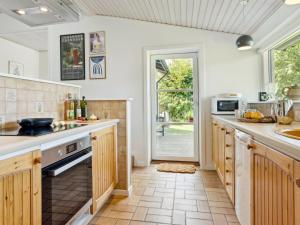 - une cuisine avec des murs blancs et des placards en bois dans l'établissement Holiday Home Floriane - 50m from the sea in NE Jutland by Interhome, à Hals