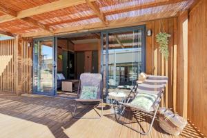 a patio with two chairs and a table on a deck at Huttopia De Meinweg in Herkenbosch +18 photos