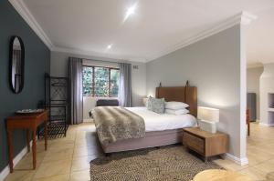 a bedroom with a bed and a desk and a window at Stony Brook Cottages in Franschhoek