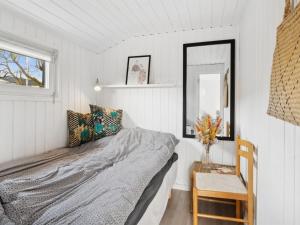 ein Schlafzimmer mit einem Bett, einem Spiegel und einem Stuhl in der Unterkunft Holiday Home Kielo - all inclusive - 200m to the inlet by Interhome in Løgstør