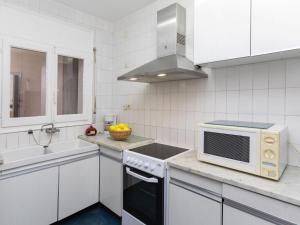 a white kitchen with a microwave and a sink at Apartment Riells Platja by Interhome in L'Escala