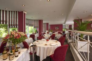 un restaurante con mesas blancas, sillas rojas y botellas de vino en Grand Hôtel de Solesmes - Teritoria en Solesmes