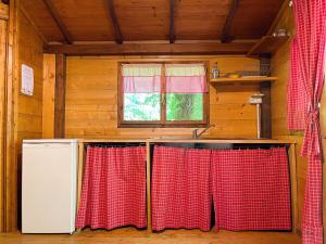 una cocina con cortinas rojas y blancas y fregadero en Le sorgenti - Chalet 57, en Palazzuolo sul Senio