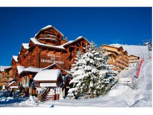 a ski lodge with a snow covered tree in front of it at Grandes Rousses Hotel & Spa in L'Alpe-d'Huez