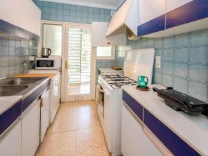 una cocina con armarios blancos y azulejos azules en Apartment Els Pins by Interhome, en Sant Vicenç de Montalt