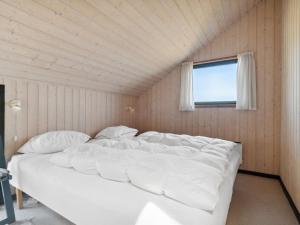 uma grande cama branca num quarto com uma janela em Holiday Home Henri - 500m from the sea in NW Jutland by Interhome em Fjerritslev