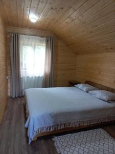 a bed in a wooden room with a window at На горі in Vorokhta