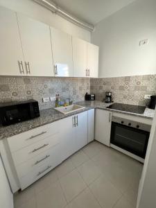 a kitchen with white cabinets and a sink at EVA'S HOME in Bizerte