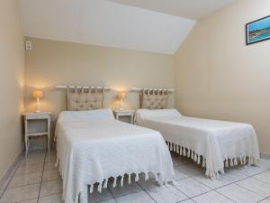 twee bedden in een kamer met witte lakens en lampen bij Holiday Home opale by Interhome in Saint-Coulomb