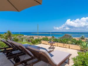 eine Terrasse mit Stühlen, einem Sonnenschirm und dem Meer in der Unterkunft Holiday Home Las Gaviotas Style & Charm by Interhome in Colonia Sant Jordi