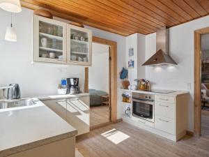 a kitchen with white cabinets and a wooden ceiling at Holiday Home Cordelia - 1km from the sea in NW Jutland by Interhome in Skagen