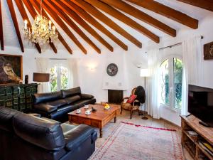 una sala de estar con muebles de cuero y una lámpara de araña. en Villa Azul Mediterraneo by Interhome en Jávea