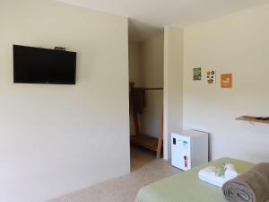 sala de estar con TV de pantalla plana en la pared en Pousada Girassol 2, en Poços de Caldas