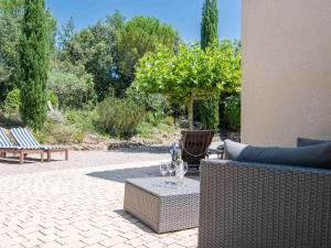 un patio con sofá y una mesa con copas de vino en Holiday Home Le Jardin du Golf by Interhome en Nans-les-Pins