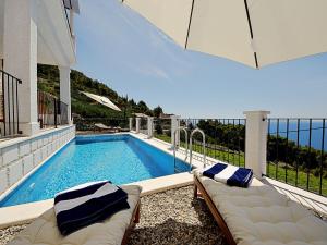 a swimming pool with two couches sitting next to a house at Holiday Home Cicak by Interhome in Sveta Nedelja