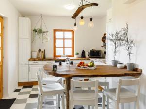 cocina con mesa de madera y sillas blancas en Holiday Home Majsa by Interhome, en Badacsonyörs
