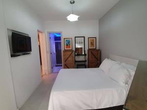 a bedroom with a white bed and a flat screen tv at Pier Sul Apartaments in Salvador