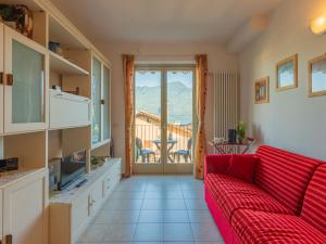 uma sala de estar com um sofá vermelho e uma varanda em Apartment Bot by Interhome em Gravedona