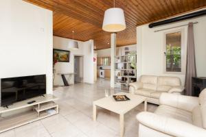 a living room with white furniture and a flat screen tv at Villa Archimedes in Peyia