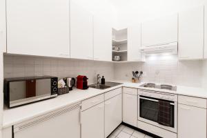 a white kitchen with white cabinets and a microwave at Maraini 17 by Quokka 360 - panoramic flat near the station in Lugano