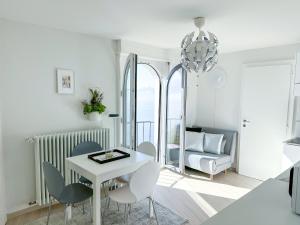 a white dining room with a white table and chairs at Room with 360° view overlooking Lake Geneva and Alps in Puidoux