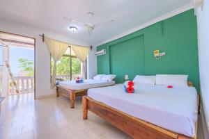 a bedroom with two beds and a green wall at Geo Zanzibar Resort in Jambiani