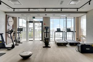 a gym with treadmills and ellipticals in a room with windows at Grano Solmarina - Marina Residence SPA&Wellness in Wiślinka