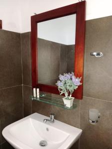 a bathroom with a sink and a mirror and flowers at Home Stay Resort in Nilaveli
