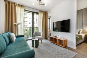 uma sala de estar com um sofá azul e uma televisão em Scala Apartments by HappyStay em Gdansk