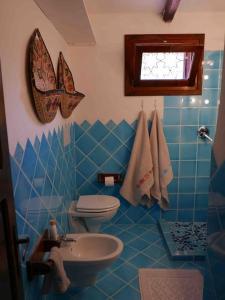 Cala BittaにあるVilla 200 mt from the beach - Baja Sardiniaの青いタイル張りのバスルーム(トイレ、シンク付)