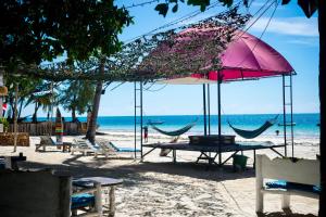 a picnic table and chairs on the beach with an umbrella at Soul Breeze Backpackers Diani in Diani Beach