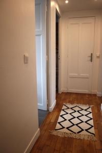 a hallway with a white door and a black and white rug at Magnifique Appartement proche Stade de France in Saint-Denis
