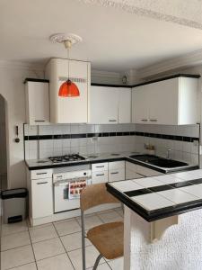 uma cozinha com armários brancos e um forno com placa de fogão em T2 indépendant proche OL Stadium et salle LDLC Arena em Meyzieu